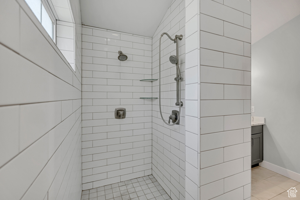 Full bath featuring tiled shower, vanity, and tile patterned flooring