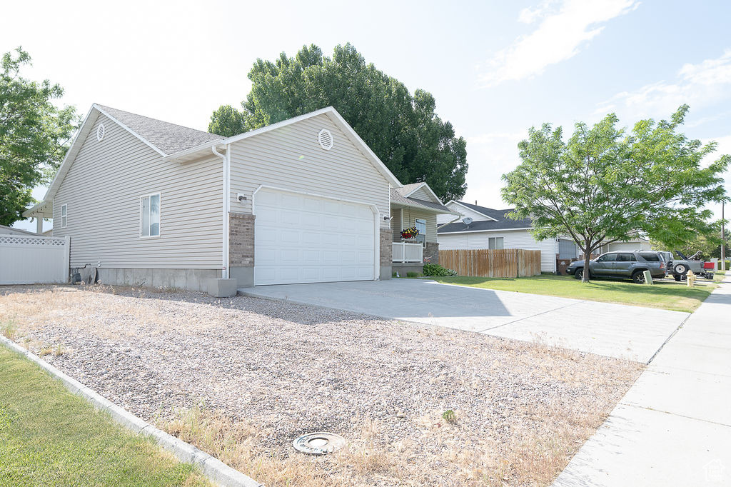 View of property exterior featuring concrete driveway, an attached garage, and brick siding