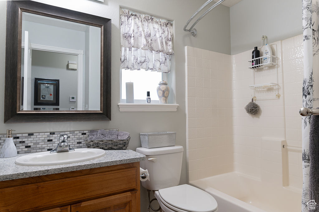 Bathroom featuring vanity, tasteful backsplash, and  shower combination