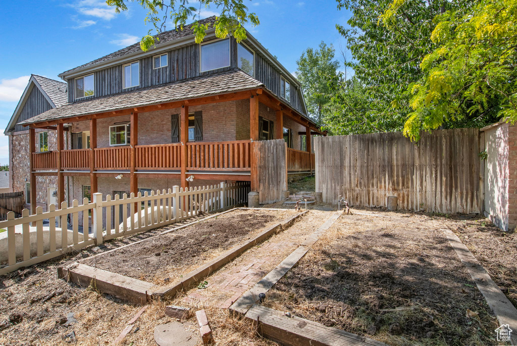 View of front of property featuring brick siding, a vegetable garden, and a fenced backyard