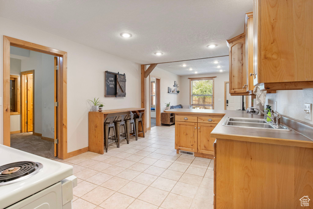 Kitchen featuring stove, recessed lighting, light tile patterned floors, a peninsula, and light countertops