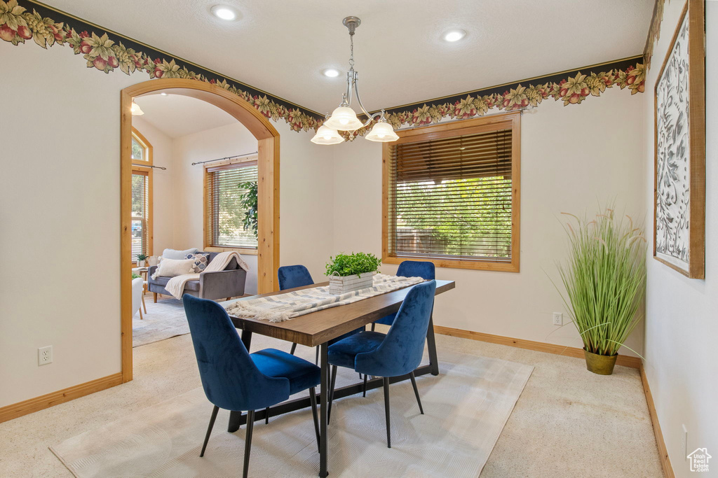 Dining space featuring arched walkways, light colored carpet, and recessed lighting