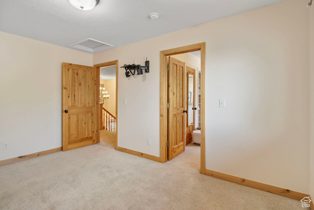 Carpeted empty room featuring a smoke detector and attic access