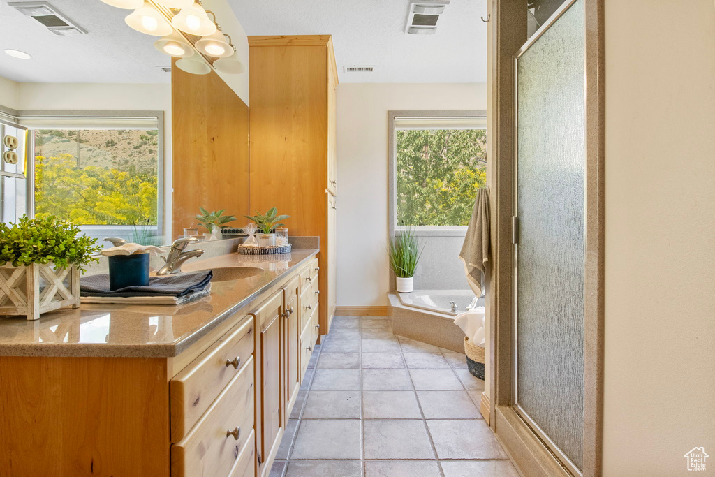 Full bathroom with vanity, a bath, a chandelier, and a shower stall