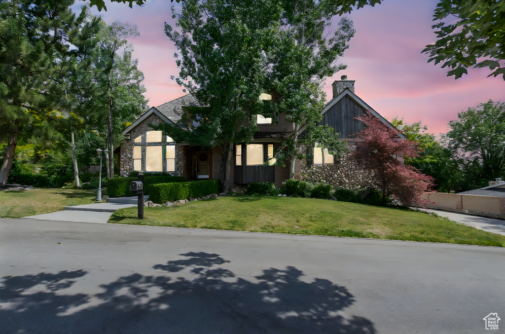 View of front of home with stone siding, a front lawn, and a chimney
