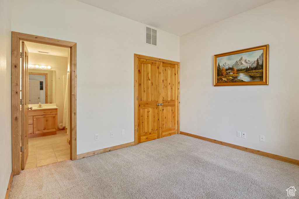 Unfurnished bedroom with carpet and ensuite bath