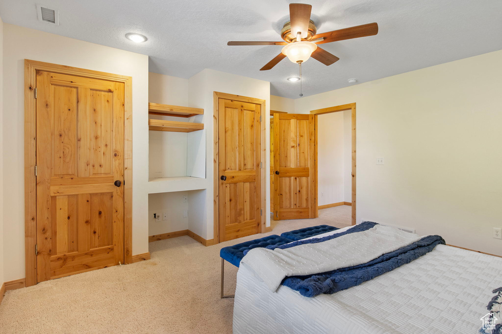 Carpeted bedroom with ceiling fan and a closet