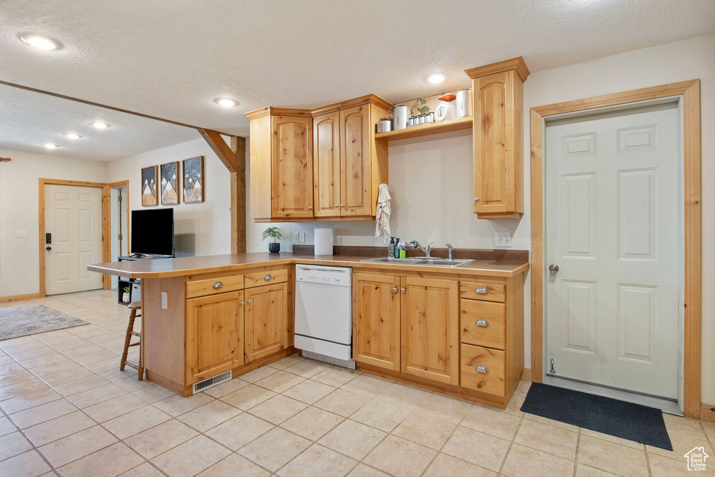 Kitchen featuring dishwasher, a peninsula, a textured ceiling, light tile patterned flooring, and recessed lighting