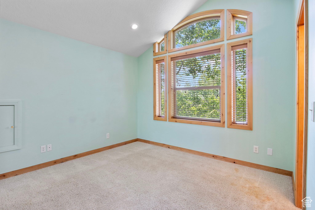 Carpeted spare room with baseboards and lofted ceiling