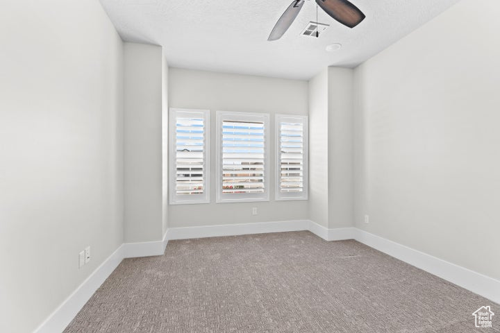 Carpeted spare room featuring ceiling fan and a textured ceiling