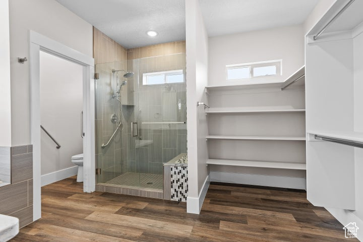 Bathroom with a shower stall, wood finished floors, and recessed lighting
