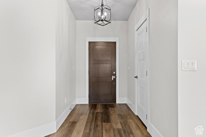 Doorway with a chandelier and dark wood-style flooring