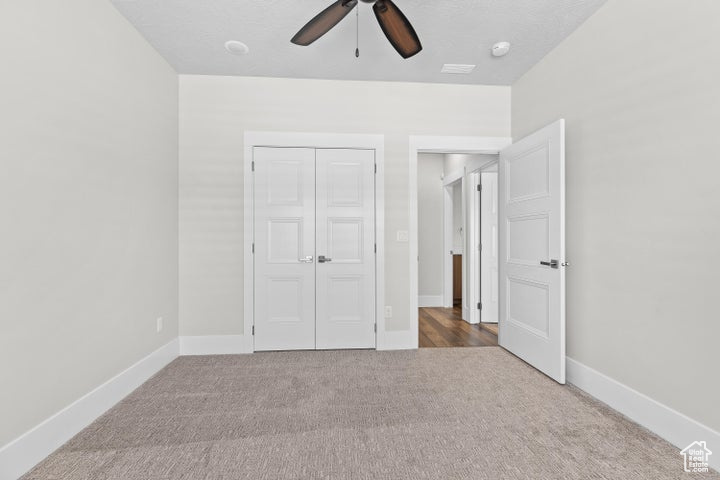 Unfurnished bedroom featuring carpet flooring, a closet, and ceiling fan