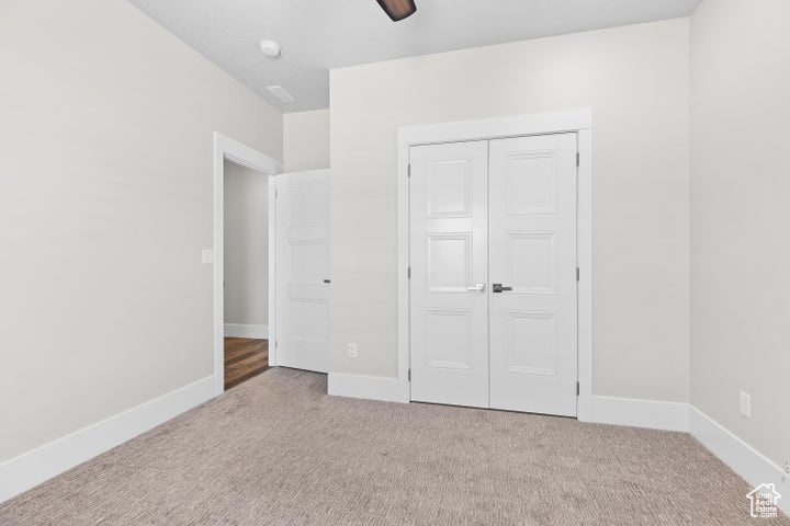 Unfurnished bedroom featuring carpet, a closet, and ceiling fan