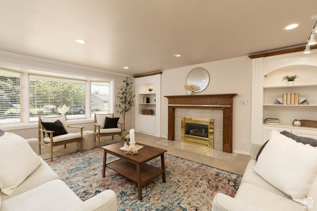 Living room featuring built in shelves, ornamental molding, a tiled fireplace, recessed lighting, and light tile patterned flooring