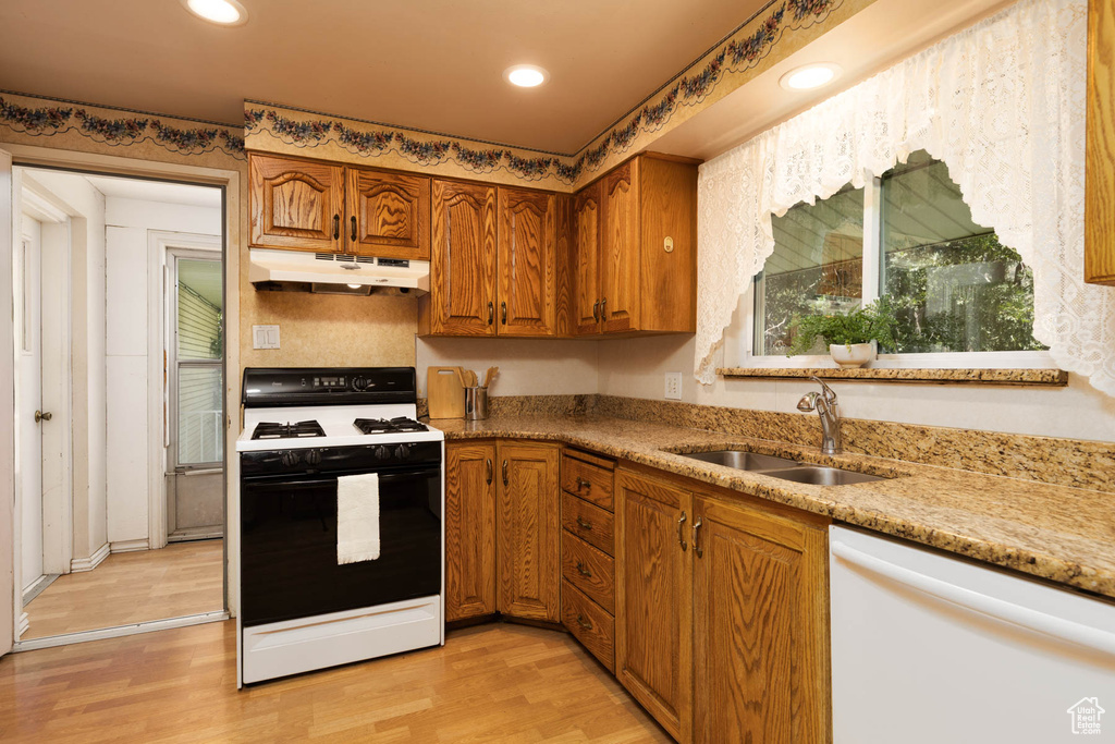 Kitchen with gas range oven, dishwasher, under cabinet range hood, brown cabinetry, and recessed lighting