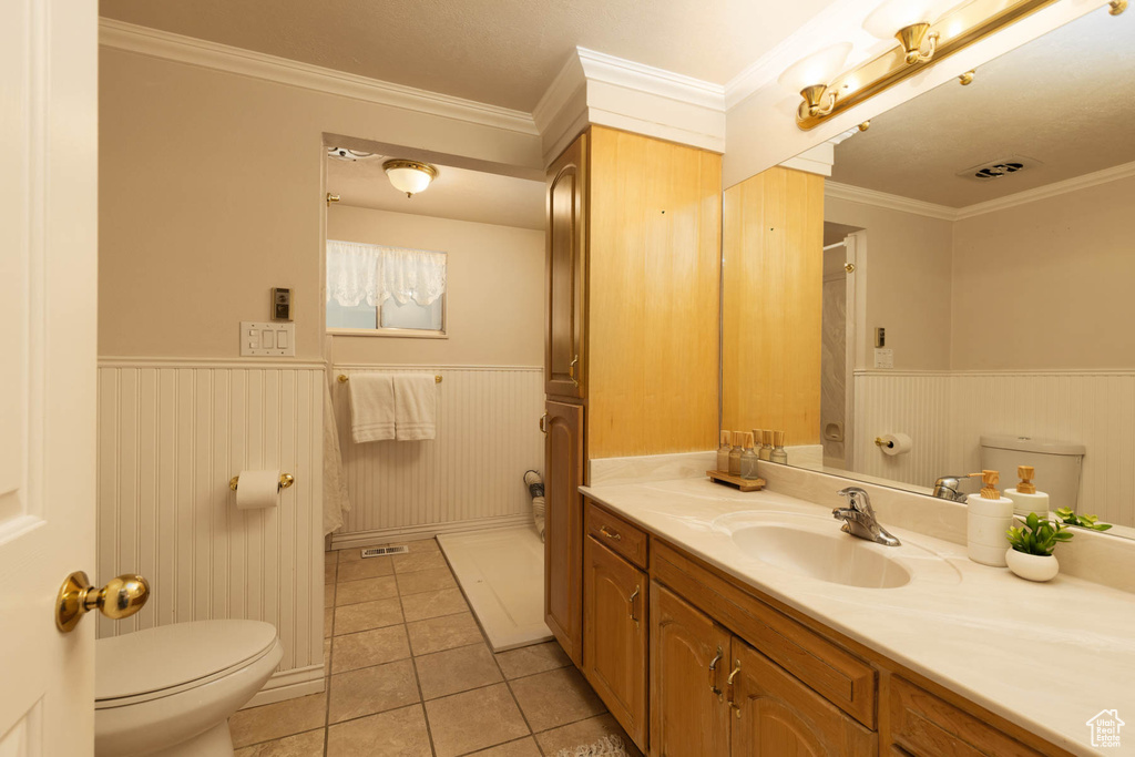 Bathroom featuring a wainscoted wall, vanity, tile patterned flooring, and crown molding