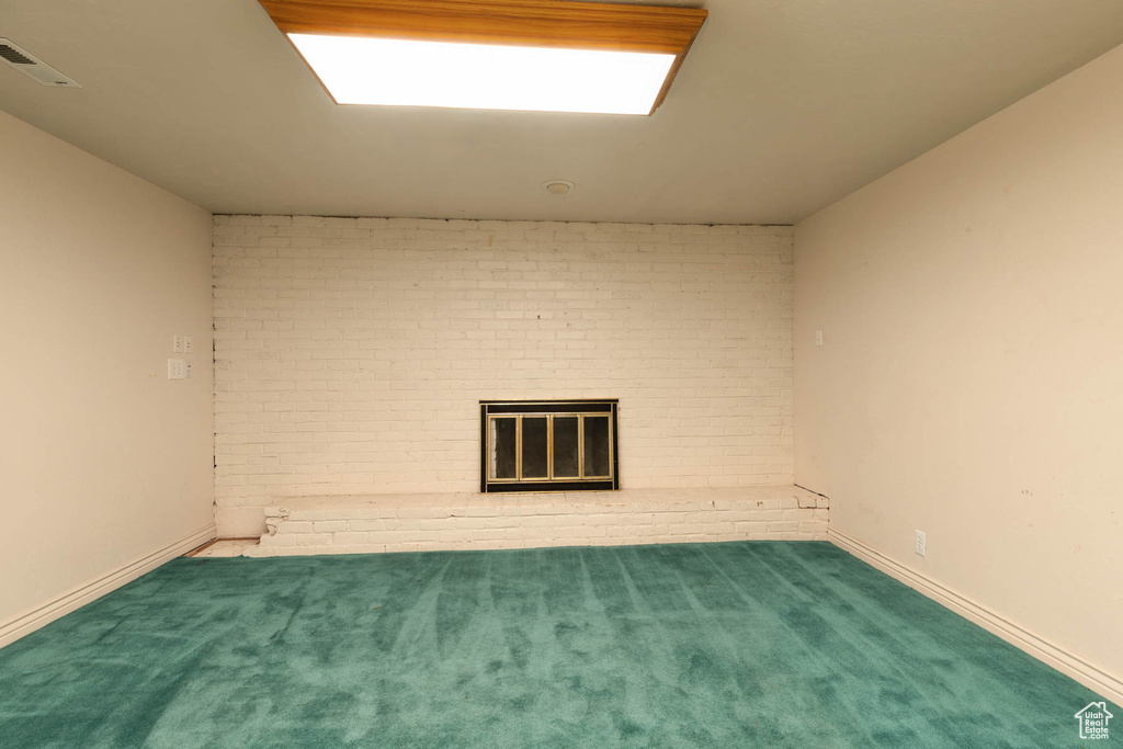 Carpeted spare room with a fireplace and baseboards