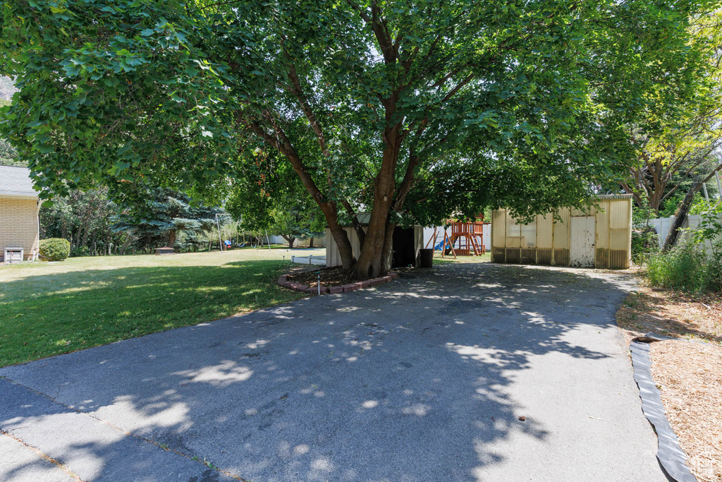View of front of home with a storage unit, a front yard, and a playground