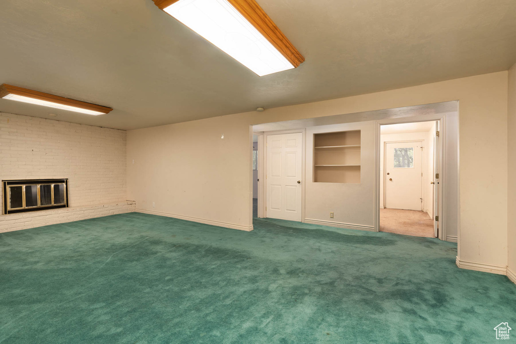 Unfurnished living room featuring carpet flooring and a brick fireplace