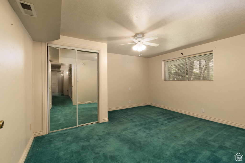 Unfurnished bedroom with carpet flooring, a closet, a textured ceiling, and ceiling fan