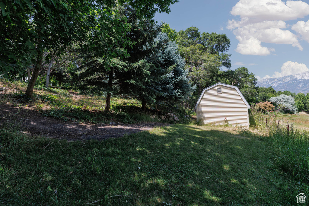 View of grassy yard with an outdoor structure and a mountain view