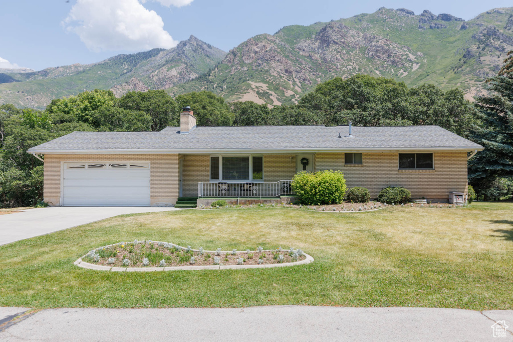 Ranch-style house featuring a porch, concrete driveway, an attached garage, a chimney, and a front lawn