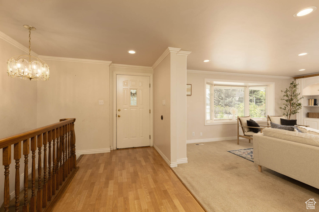 Entrance foyer with ornamental molding, recessed lighting, light wood-style floors, and a chandelier