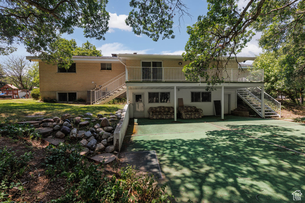 Rear view of property featuring stairway, brick siding, and a deck