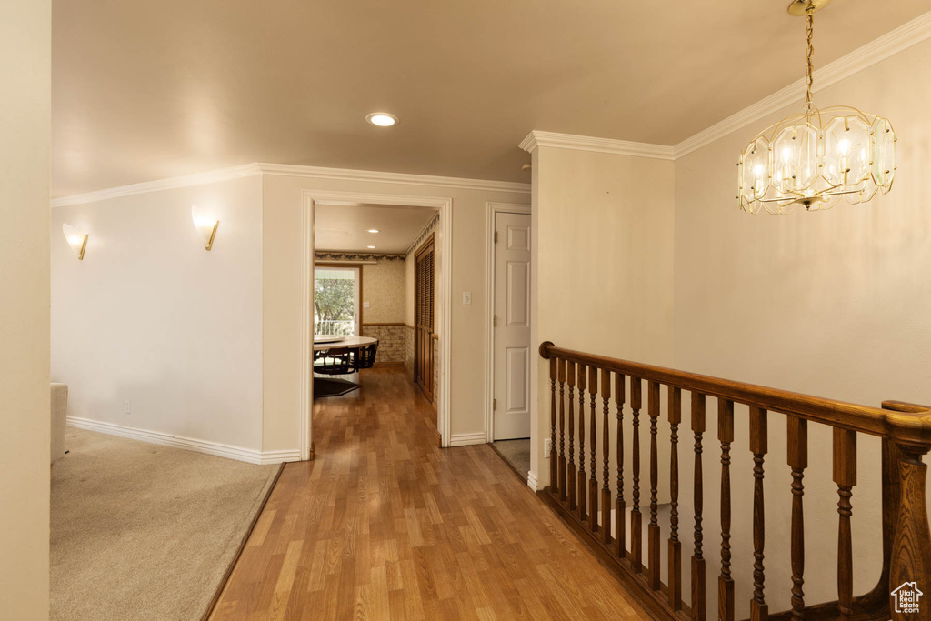 Hall featuring a chandelier, wood finished floors, crown molding, and recessed lighting