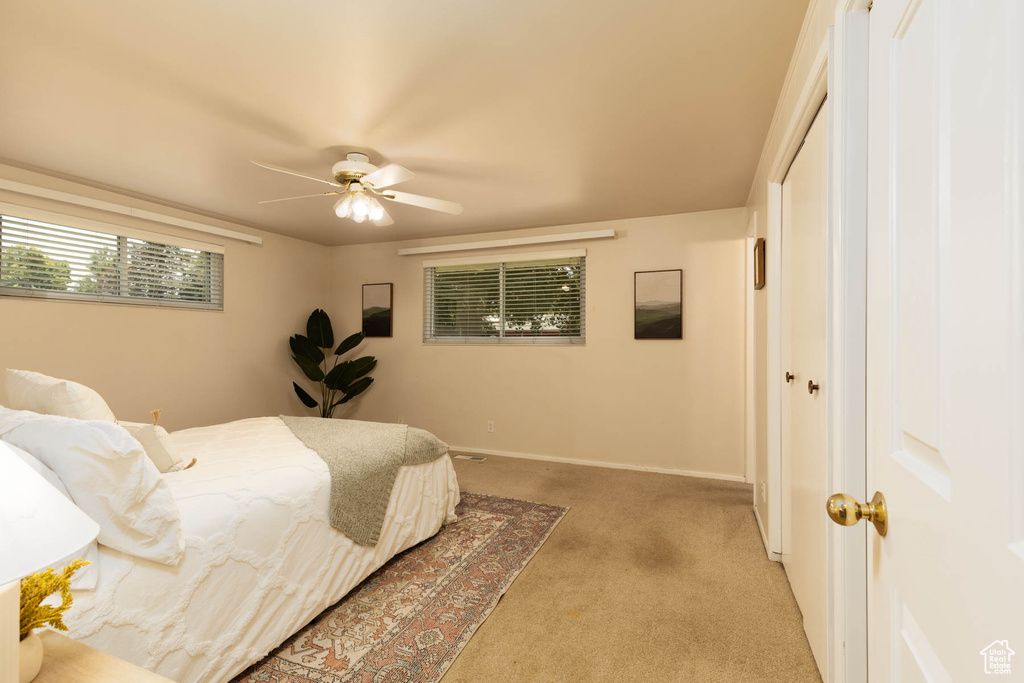 Bedroom with light carpet, a closet, and a ceiling fan