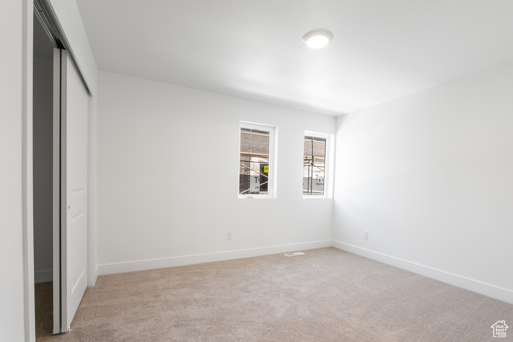 Unfurnished bedroom featuring light colored carpet and a closet