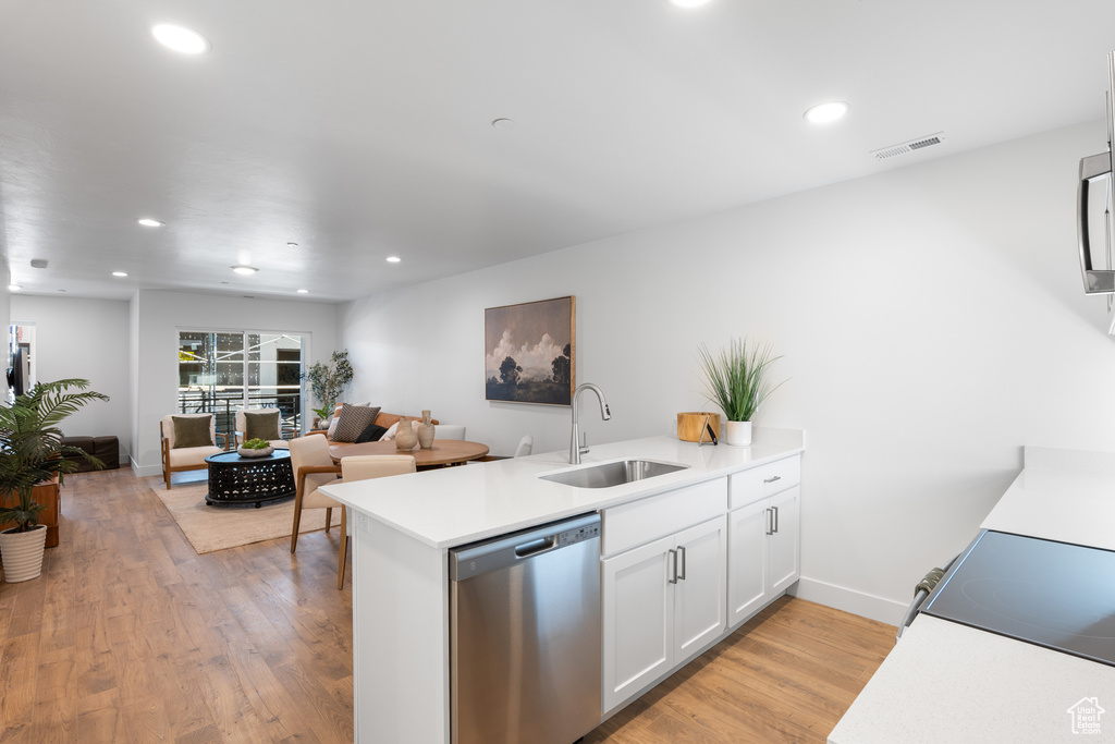 Kitchen with stainless steel appliances, a peninsula, open floor plan, white cabinets, and light countertops