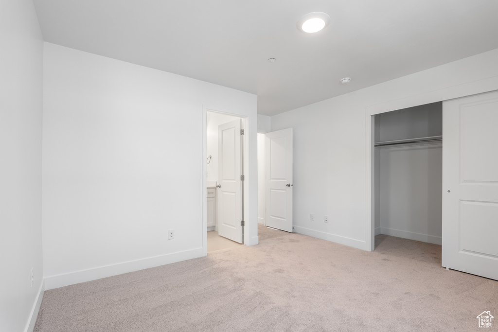 Unfurnished bedroom with carpet flooring, a closet, and ensuite bathroom