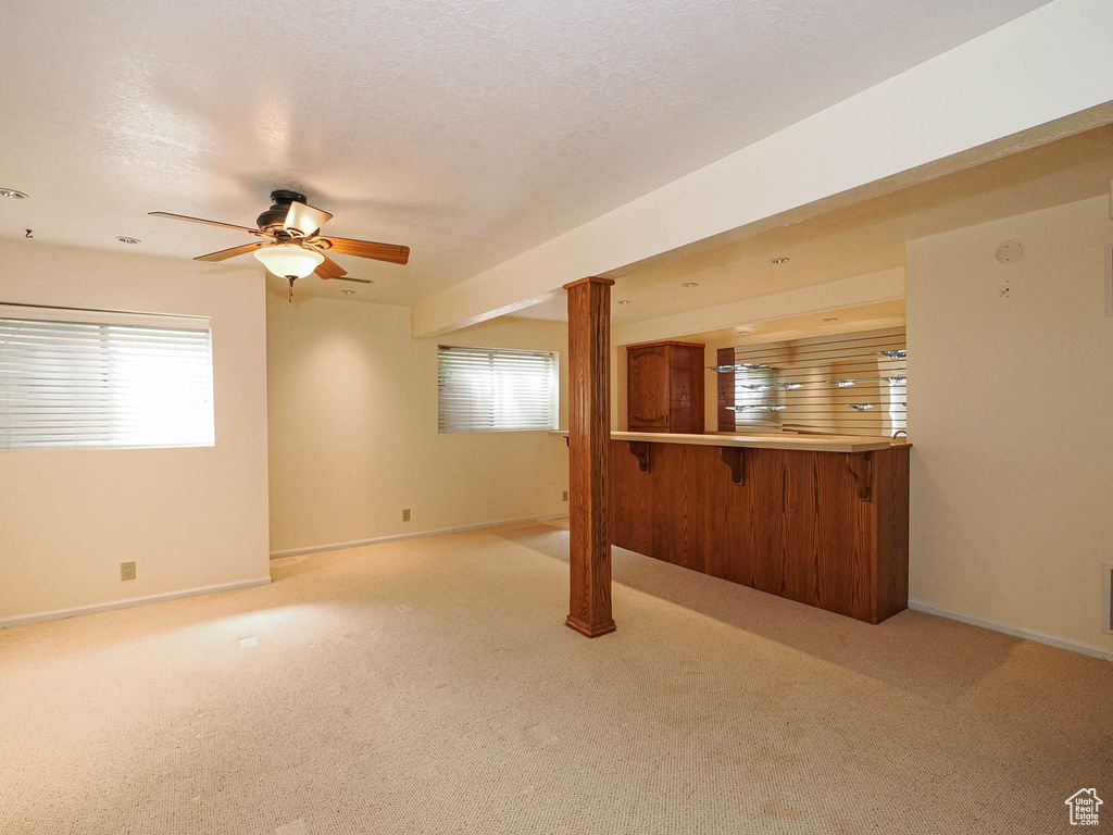 Unfurnished living room with light carpet, a ceiling fan, and healthy amount of natural light