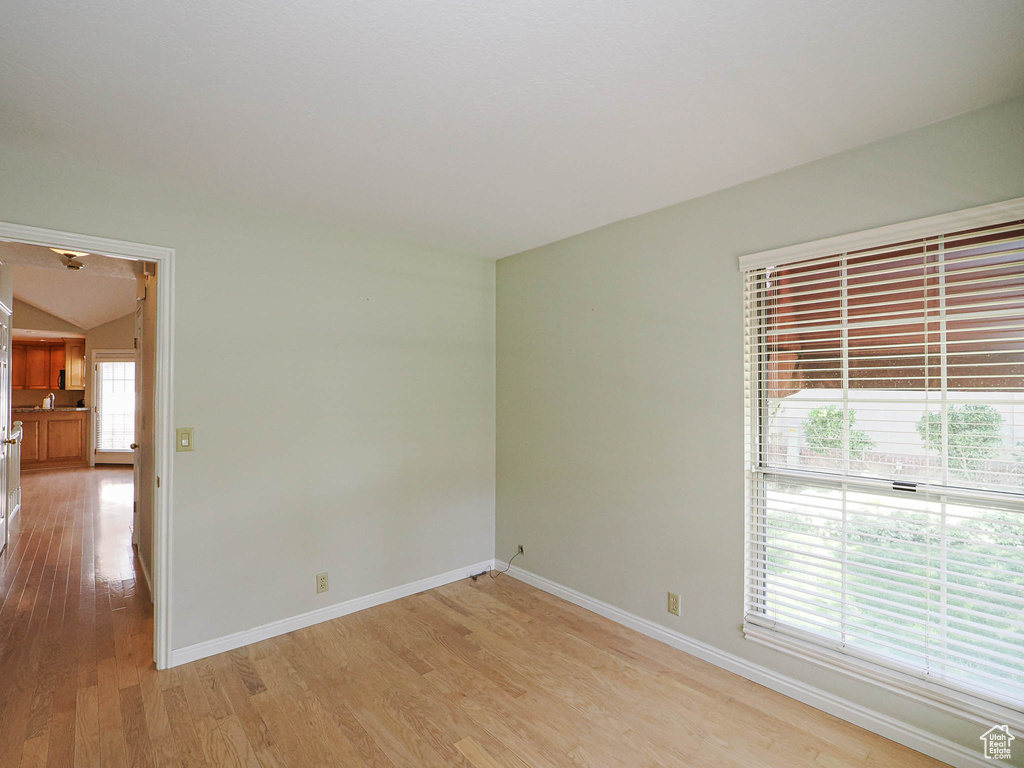 Unfurnished room with light wood-type flooring and lofted ceiling