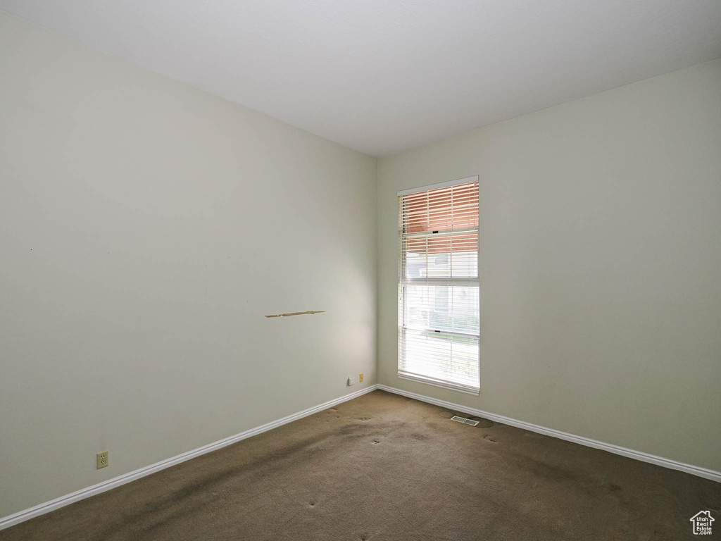 Carpeted spare room featuring baseboards