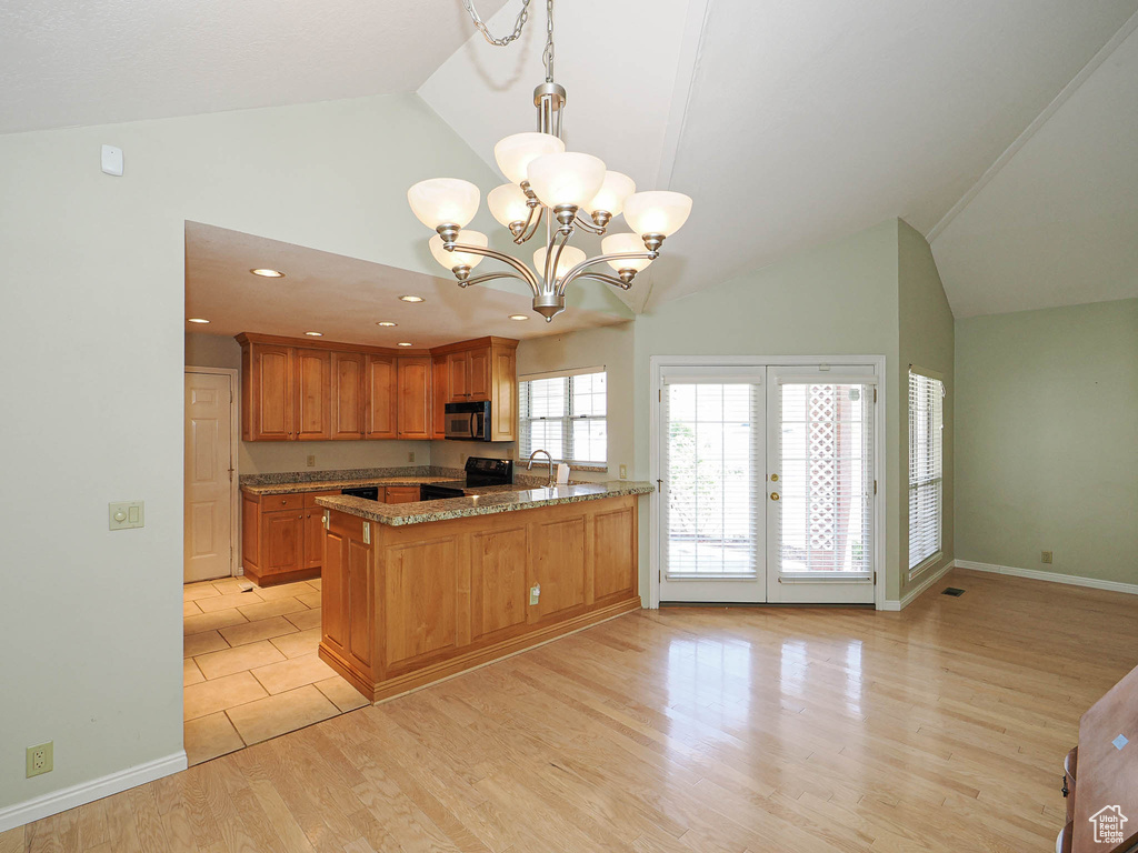 Kitchen with range with electric stovetop, french doors, high vaulted ceiling, light wood-style floors, and a peninsula