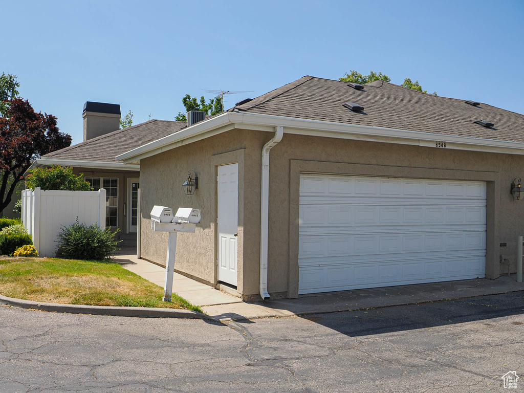 View of property exterior featuring a shingled roof, a chimney, and stucco siding