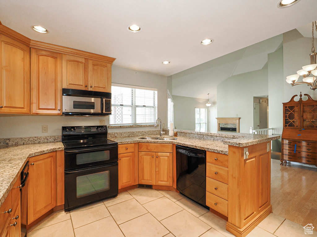 Kitchen featuring black appliances, a peninsula, plenty of natural light, recessed lighting, and light stone counters