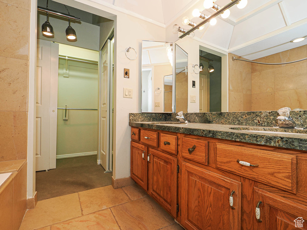 Full bath with double vanity, a bathtub, a spacious closet, and a shower