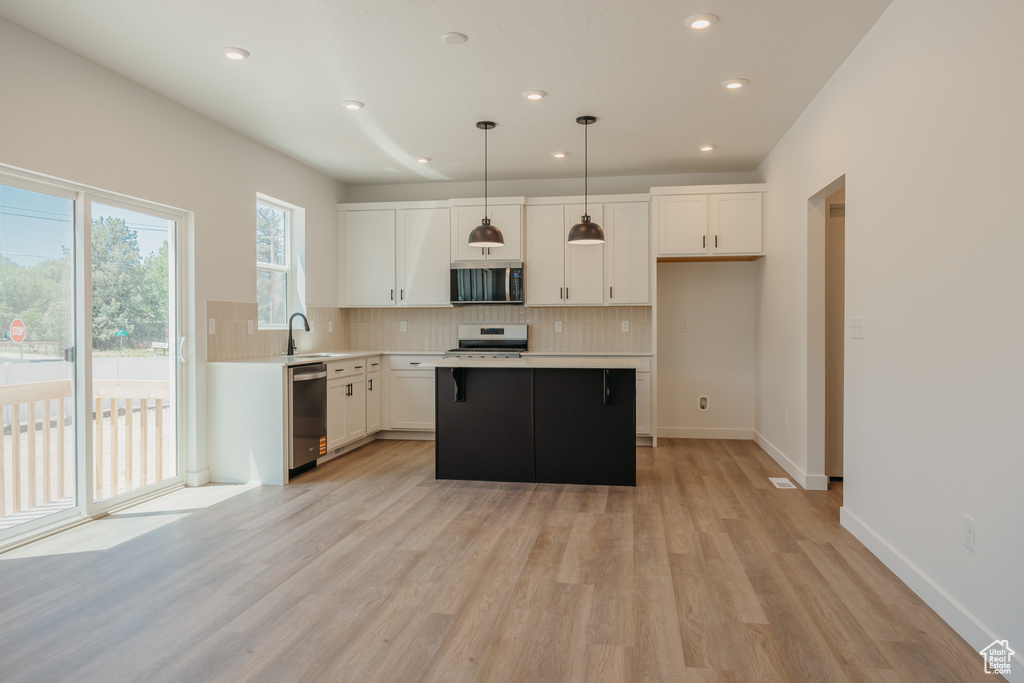 Kitchen featuring appliances with stainless steel finishes, tasteful backsplash, white cabinetry, light wood-type flooring, and recessed lighting