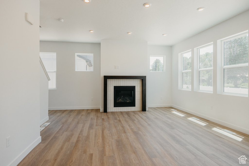 Unfurnished living room with light wood-style flooring, a tile fireplace, and recessed lighting