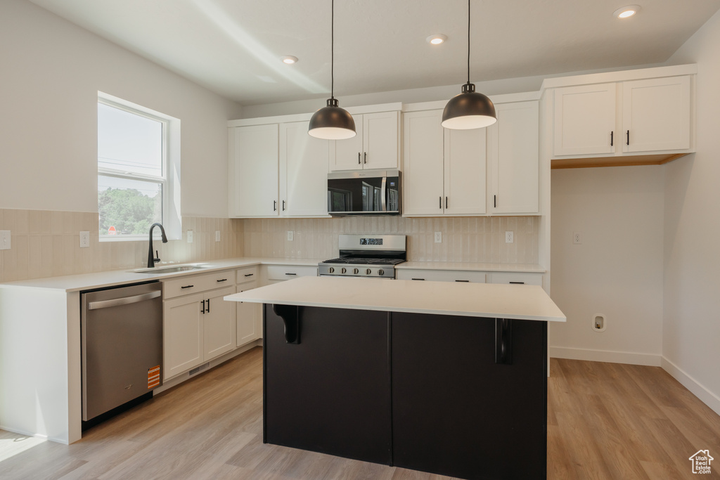 Kitchen with appliances with stainless steel finishes, recessed lighting, backsplash, light countertops, and light wood finished floors