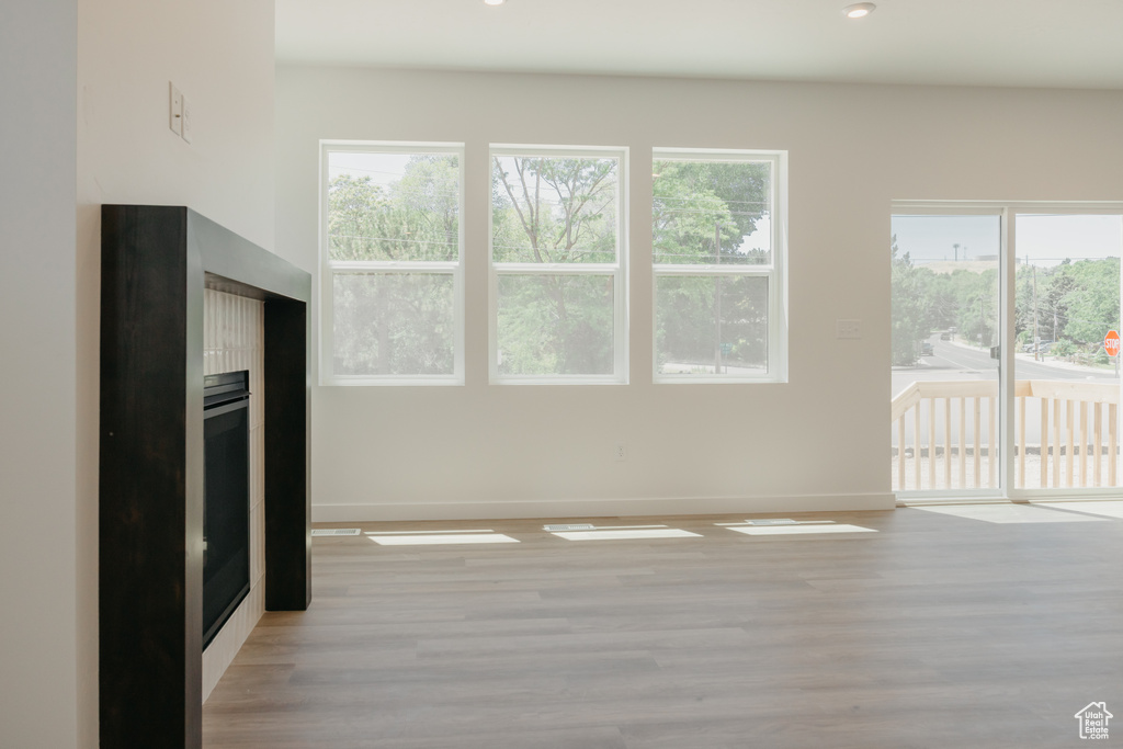 Unfurnished living room with light wood-style flooring, healthy amount of natural light, and recessed lighting