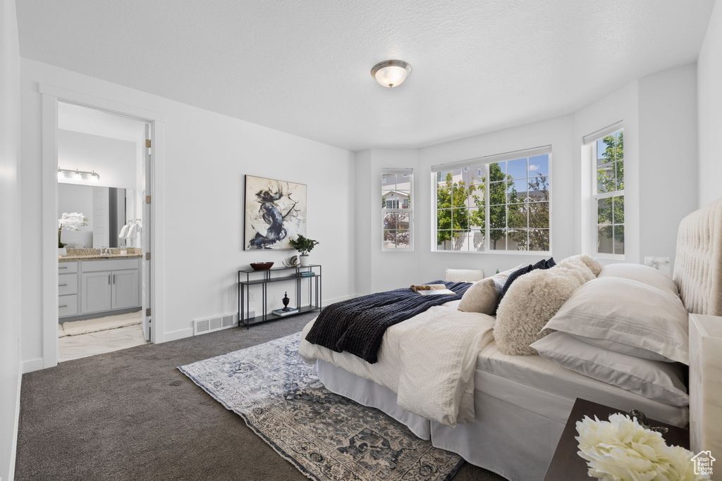 Carpeted bedroom featuring baseboards and ensuite bath