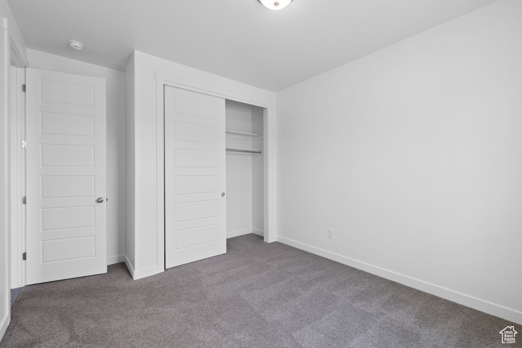 Unfurnished bedroom with dark carpet and a closet