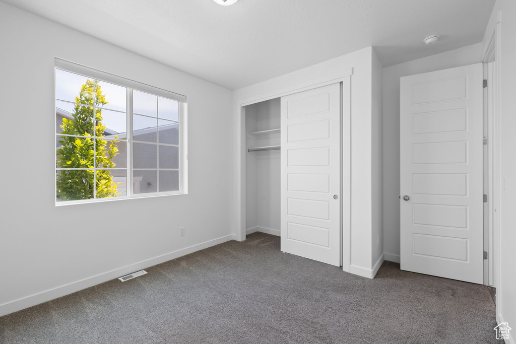 Unfurnished bedroom featuring dark colored carpet and a closet