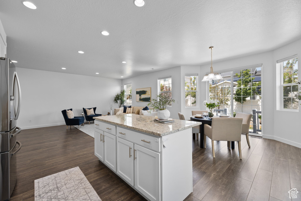 Kitchen with stainless steel fridge with ice dispenser, a kitchen island, white cabinets, dark wood-style floors, and recessed lighting