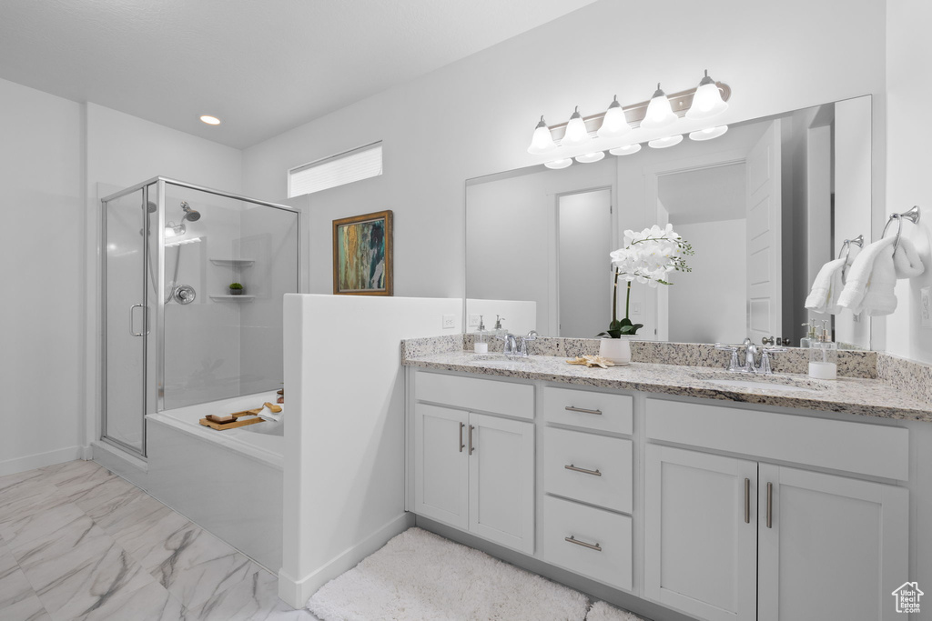 Full bath featuring a shower stall, double vanity, marble finish floors, and a bath